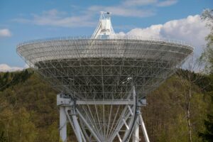 Branża kosmiczna - radioteleskop na tle drzew i nieba