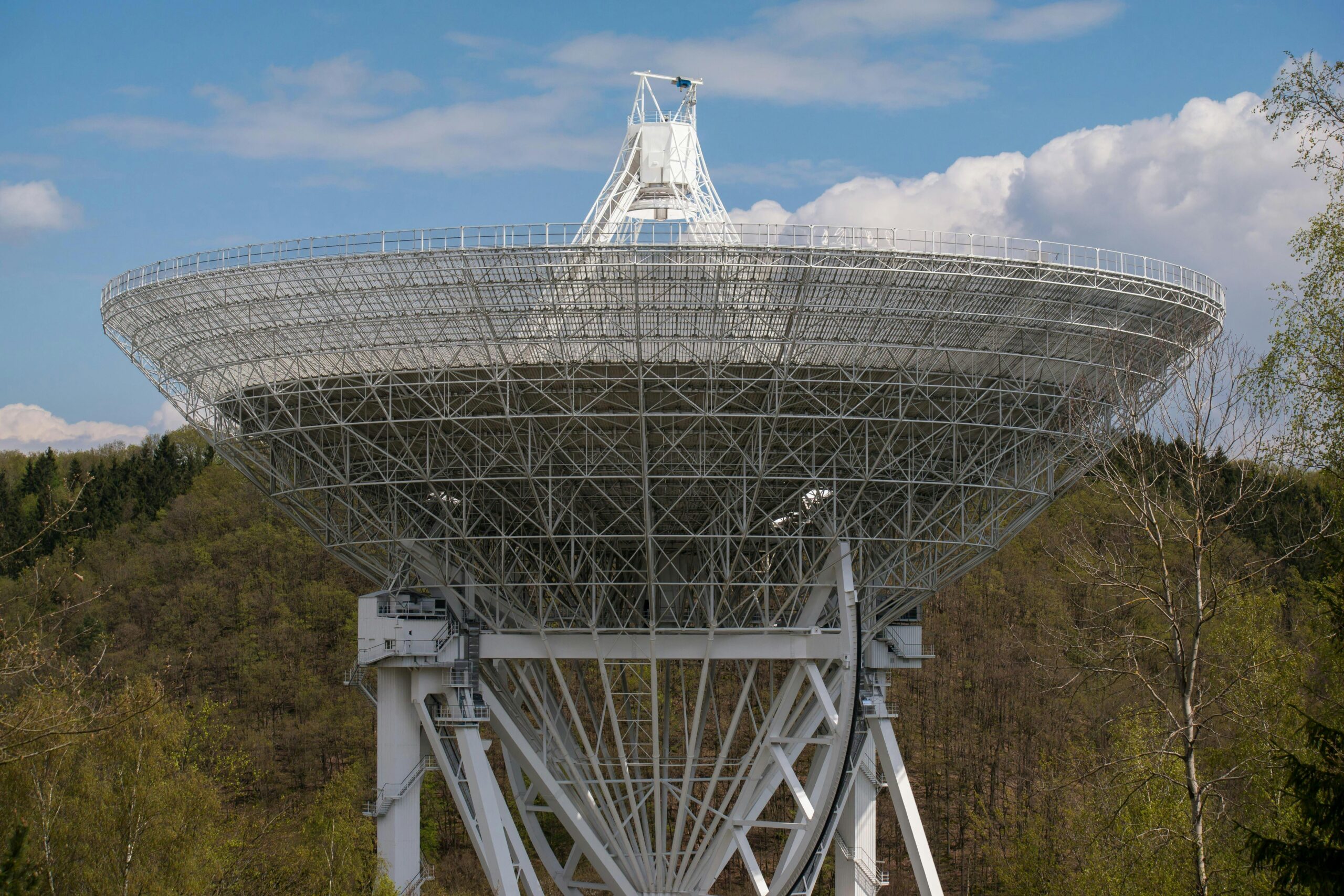 Branża kosmiczna - radioteleskop na tle drzew i nieba 